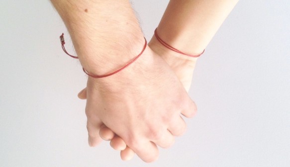 Red string bracelet with two model hands
